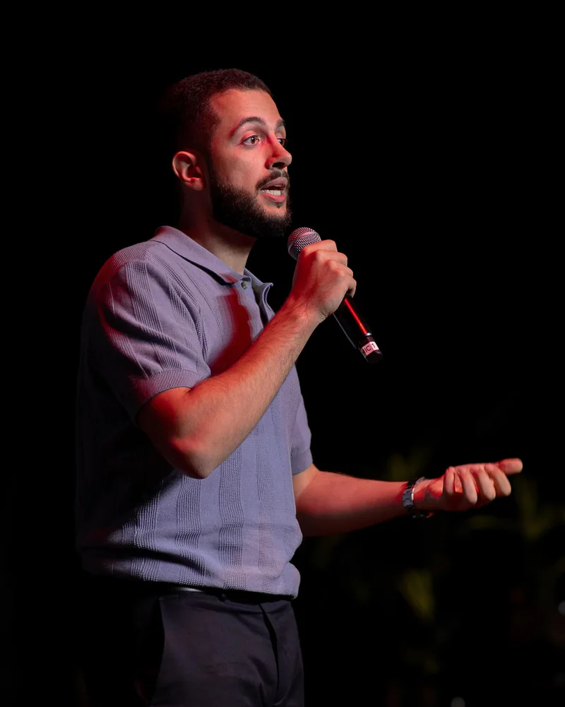 Matheus Trombino no palco, ensinando com um microfone na mão.